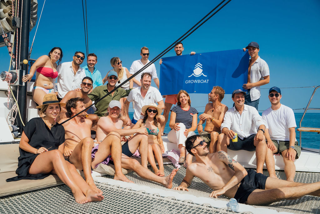 The full GrowBoat crew gathered behind the GrowBoat flag on the catamaran