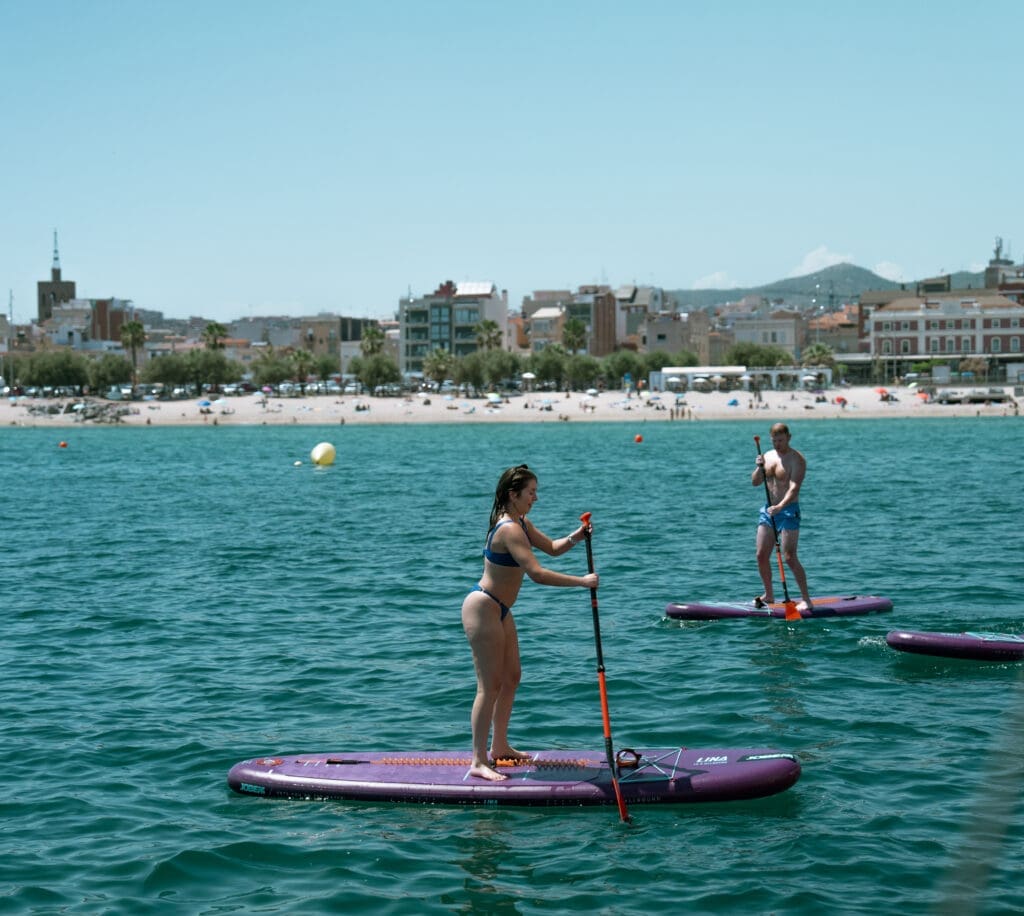 GrowBoat Barcelona guests wading into the sea from the anchored yacht