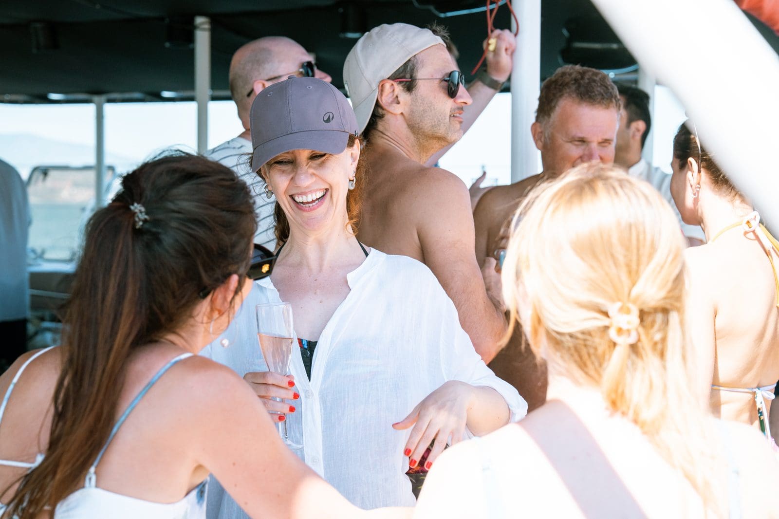 Candid group of GrowBoat guests laughing mid-conversation on the catamaran deck off Barcelona