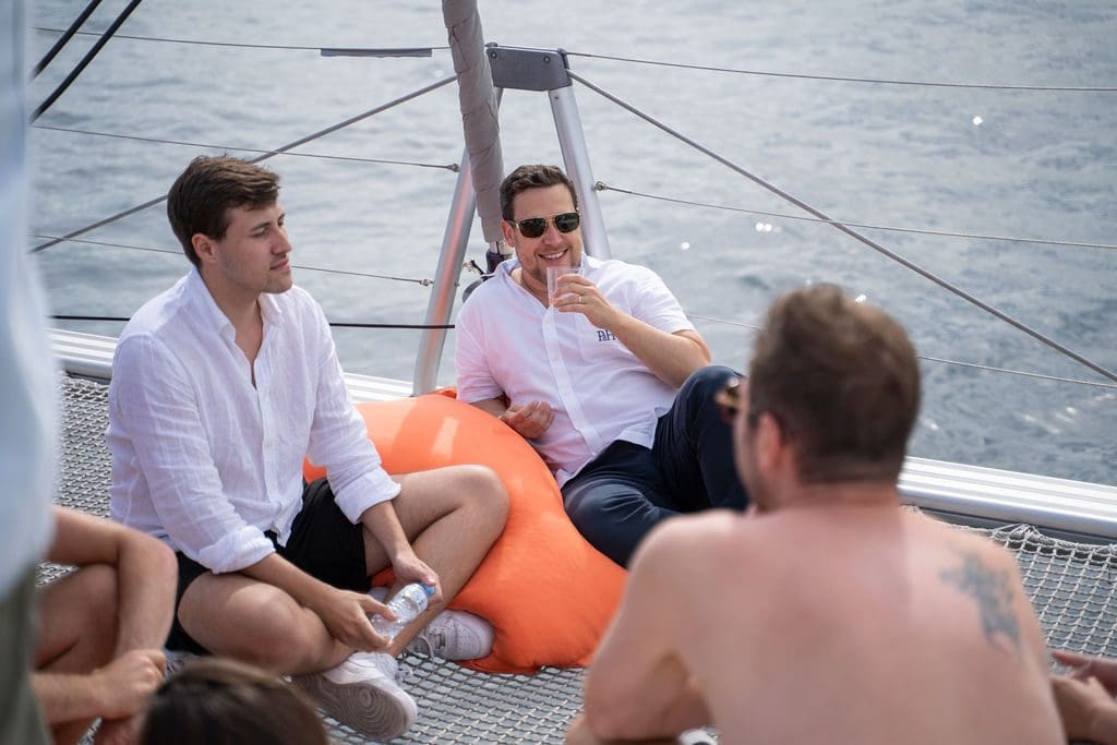 GrowBoat guests in a conversation circle on the catamaran deck at a past edition