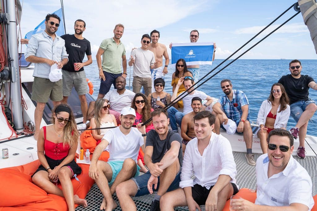 A group of GrowBoat guests relaxing on the catamaran deck at a previous sailing