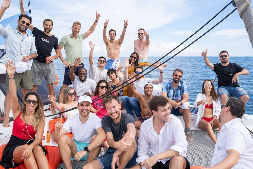 GrowBoat guests raising their arms and cheering together on the catamaran deck at a past edition