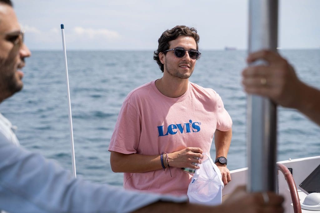 A GrowBoat guest with a drink by the rail of the catamaran at a past edition